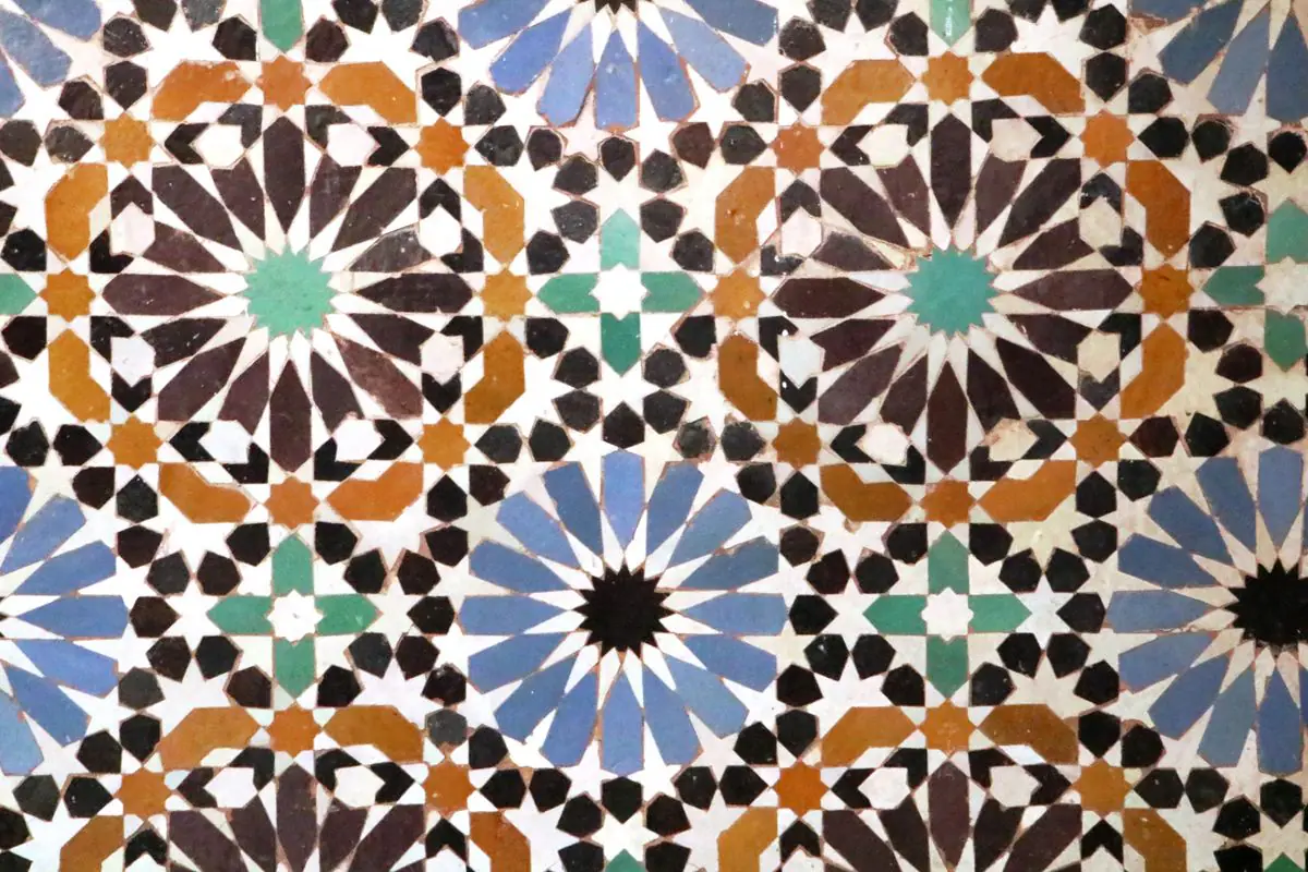 A close view of interlaced zellige stars in blue, ochre, brown and white with turquoise centres.